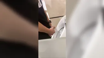 A male is pissing in the toilet.