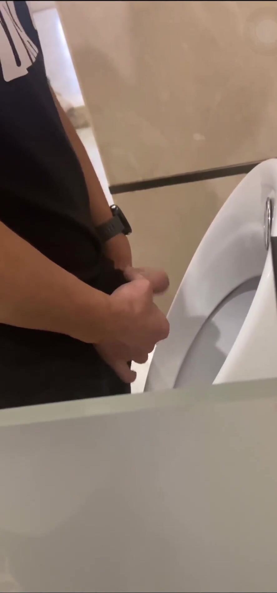 A male is pissing in the toilet.