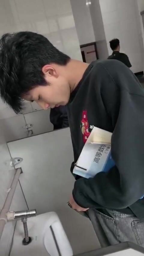 A male student is pissing in the toilet. 11