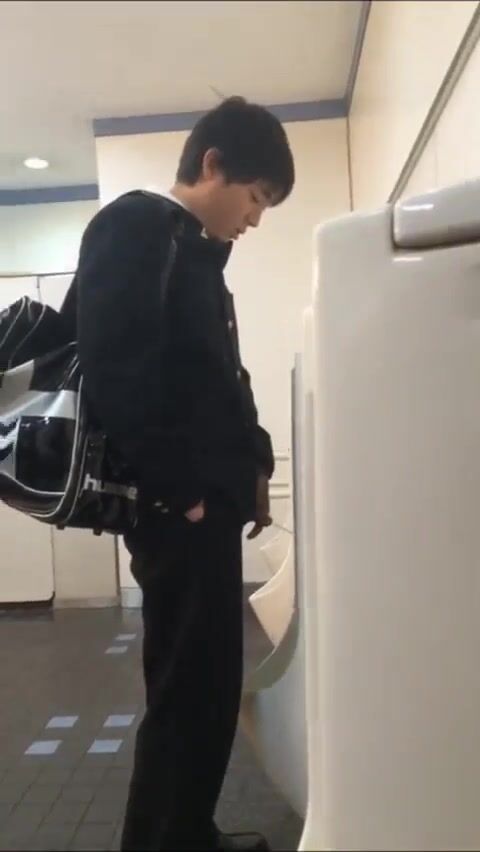 A male student is pissing in the toilet. 12